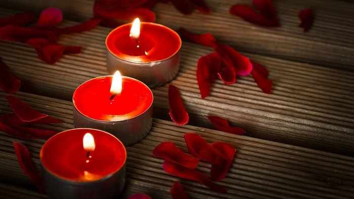 Три красные свечи и лепестки цветов